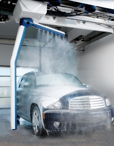 A car is being sprayed with soap by an automatic car wash machine